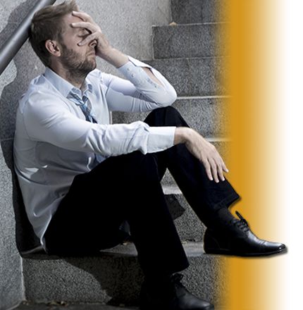 Man sitting on stairs with head in hand.