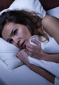 Woman having trouble falling asleep in bed
